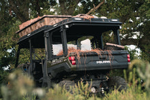 Load image into Gallery viewer, Lower rear full view of UTV featuring Swamp Ox roof rack in outdoor setting during the day. Black textured powder-coated hood and bed racks carrying outdoor gear and duck hunting equipment. Includes light package, unlit.
