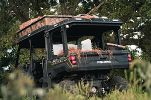 Lower rear full view of UTV featuring Swamp Ox roof rack in outdoor setting during the day. Black textured powder-coated hood and bed racks carrying outdoor gear and duck hunting equipment. Includes light package, unlit.