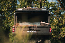 Load image into Gallery viewer, Lower rear view of UTV featuring Swamp Ox hood and bed rack in outdoor setting during the day. Black textured powder-coated hood rack carrying outdoor gear and duck hunting equipment. Includes light package, unlit.
