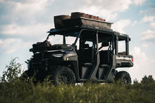 Load image into Gallery viewer, Front angled view of UTV featuring Swamp Ox hood rack, roof rack, and bed racks in grassy outdoor field. Black textured powder-coated racks all carrying outdoor gear.
