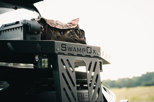 Angled closeup front view of UTV featuring Swamp Ox hood rack in outdoor setting during the day. Black textured powder-coated hood rack carrying outdoor gear.