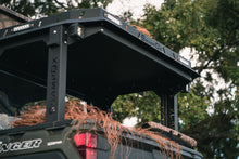 Load image into Gallery viewer, Angled closeup rear view of UTV featuring Swamp Ox roof rack in outdoor setting during the day. Black textured powder-coated hood rack carrying outdoor gear. Includes light package, unlit.
