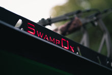 Load image into Gallery viewer, Closeup from lower left of red backlit Swamp Ox logo on roof rack.
