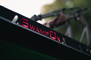 Closeup from lower left of red backlit Swamp Ox logo on roof rack.