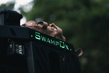 Load image into Gallery viewer, Closeup from below of green backlit Swamp Ox logo on front hood rack.
