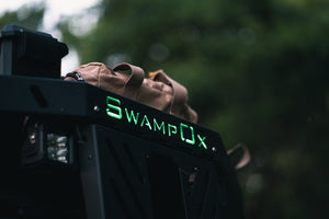 Closeup from below of green backlit Swamp Ox logo on front hood rack.