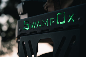 Closeup of green backlit Swamp Ox logo on front hood rack.